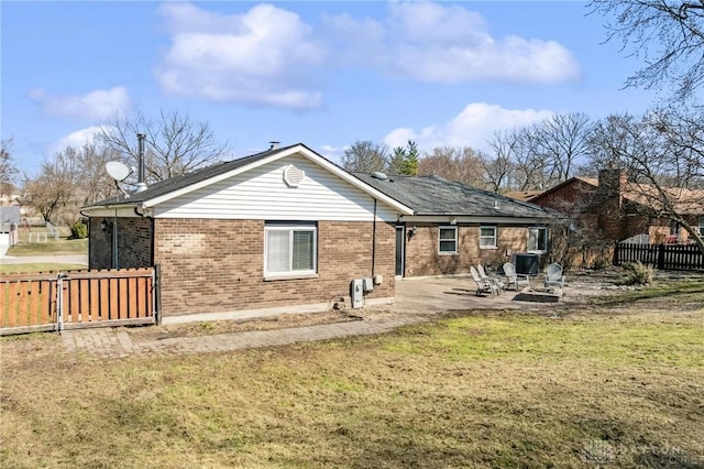 rear view of house featuring central AC unit, fence, a lawn, a patio area, and brick siding