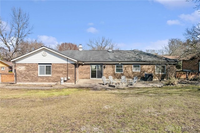 rear view of property with brick siding, fence, an outdoor fire pit, a lawn, and cooling unit