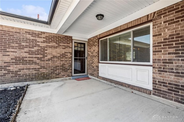 doorway to property with brick siding and a patio