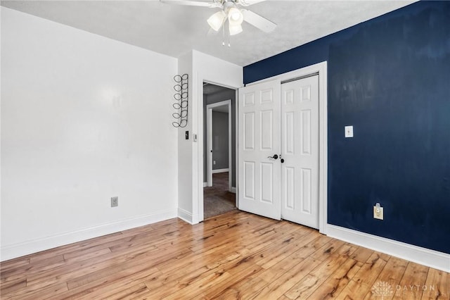 unfurnished bedroom with light wood-type flooring, baseboards, a closet, and a ceiling fan