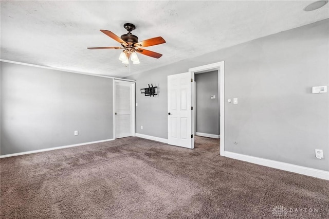 unfurnished bedroom with dark carpet, a textured ceiling, a ceiling fan, and baseboards