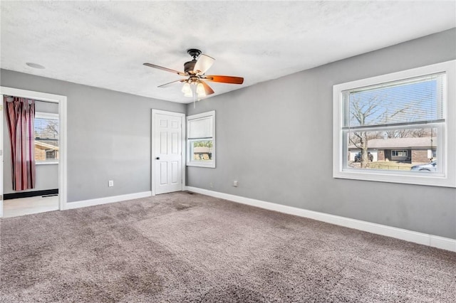 unfurnished room with baseboards, carpet, a ceiling fan, and a textured ceiling