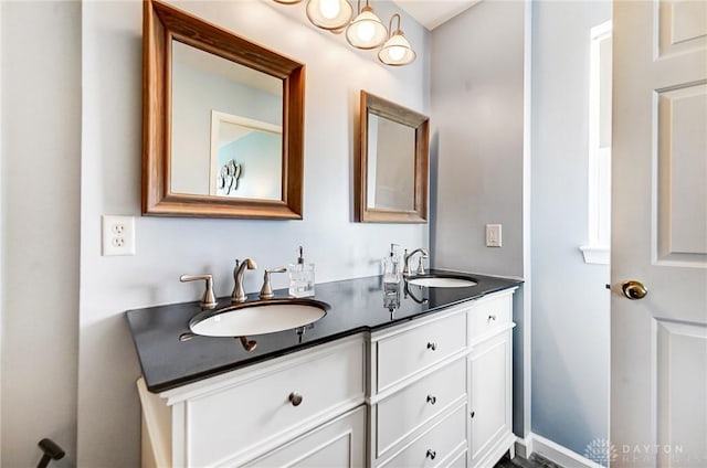 bathroom featuring double vanity, baseboards, and a sink