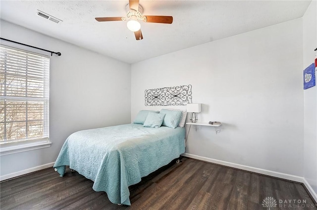 bedroom with visible vents, multiple windows, baseboards, and wood finished floors