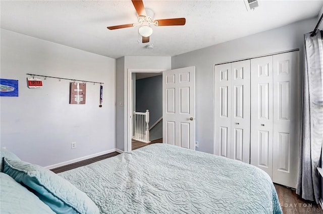 bedroom featuring visible vents, baseboards, dark wood-style flooring, ceiling fan, and a closet