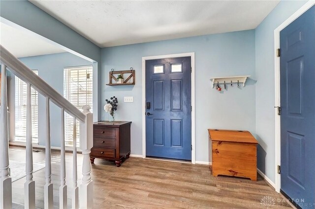 foyer entrance with stairs, light wood-style flooring, and baseboards