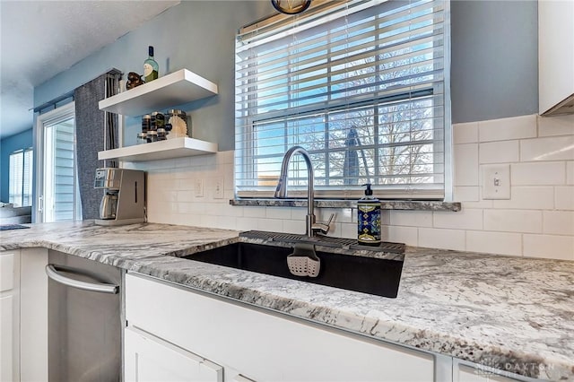 kitchen featuring light stone counters, a wealth of natural light, and a sink