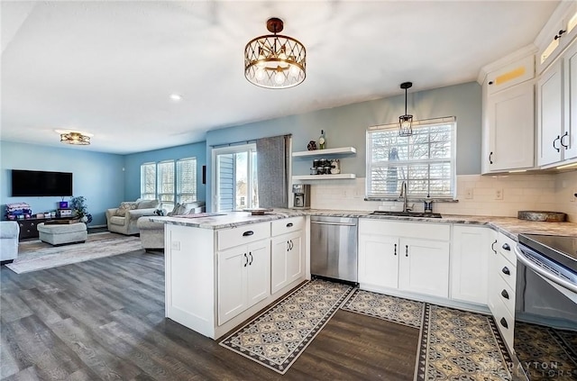 kitchen with a sink, appliances with stainless steel finishes, a peninsula, and white cabinets