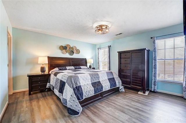 bedroom featuring visible vents, baseboards, and wood finished floors