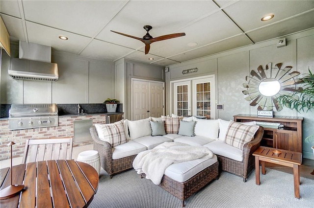 living room featuring a decorative wall, a ceiling fan, and carpet floors