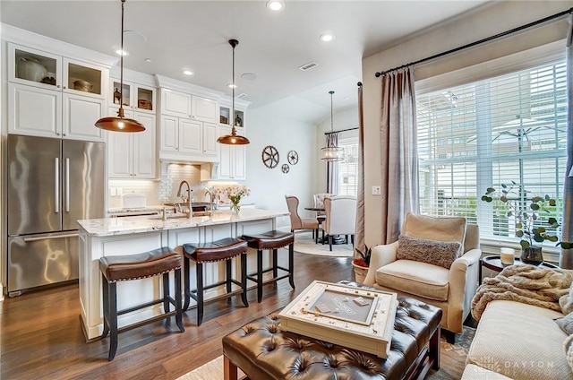 living area with a wealth of natural light, visible vents, dark wood finished floors, and recessed lighting