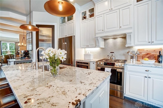 kitchen with decorative light fixtures, tasteful backsplash, appliances with stainless steel finishes, glass insert cabinets, and light stone countertops