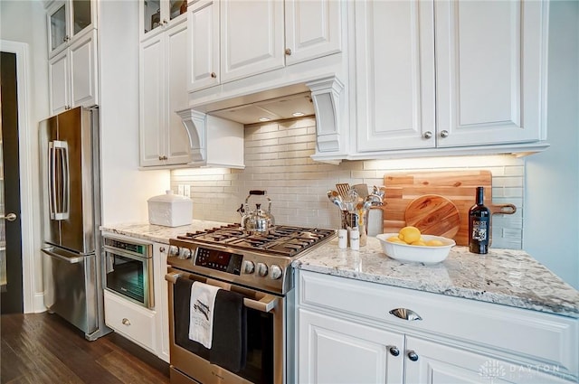 kitchen featuring glass insert cabinets, light stone countertops, appliances with stainless steel finishes, and white cabinetry