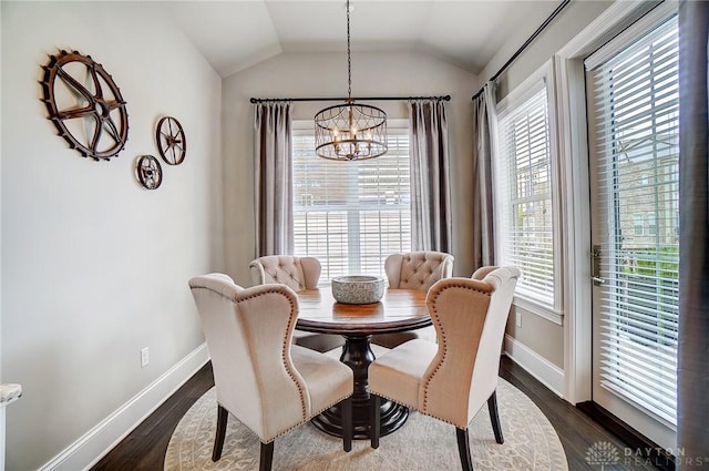 dining room featuring lofted ceiling, plenty of natural light, dark wood-type flooring, and an inviting chandelier