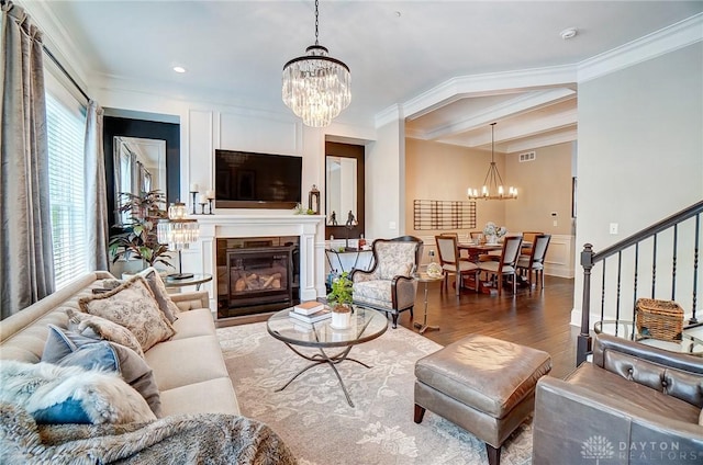 living area with a chandelier, stairway, crown molding, and wood finished floors