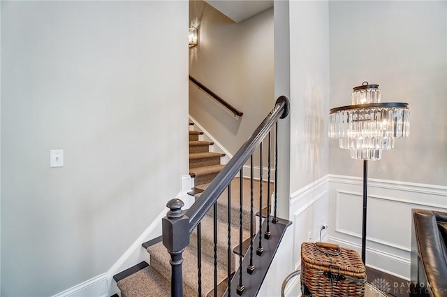 stairway featuring a decorative wall and wainscoting