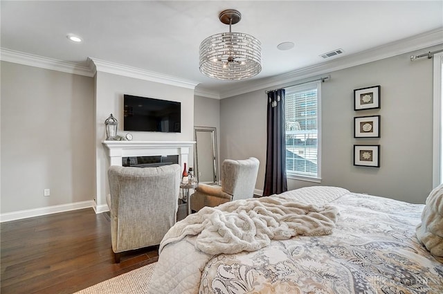 bedroom featuring visible vents, baseboards, dark wood finished floors, ornamental molding, and a glass covered fireplace