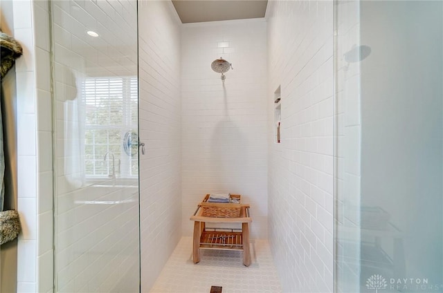 bathroom featuring tile patterned floors, tile walls, and a tile shower