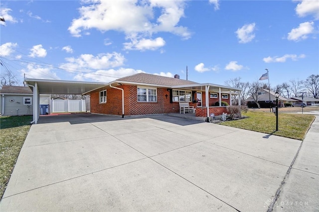 view of front facade with driveway, a porch, a carport, a front lawn, and brick siding