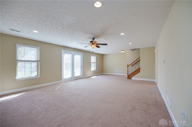 spare room with stairs, baseboards, visible vents, and a textured ceiling