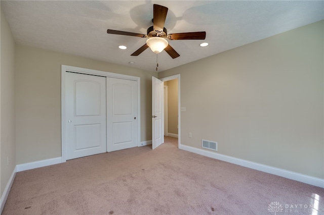 unfurnished bedroom with a closet, visible vents, light colored carpet, and baseboards