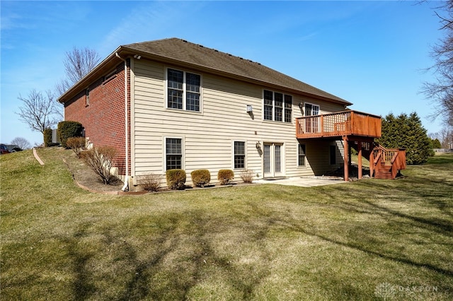 rear view of property featuring a yard, a patio, brick siding, and a deck