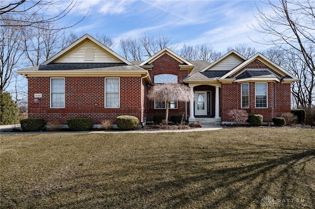 view of front of house featuring brick siding, a shingled roof, and a front yard