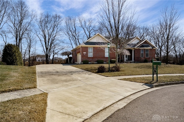 view of front of home with brick siding, a garage, driveway, and a front lawn