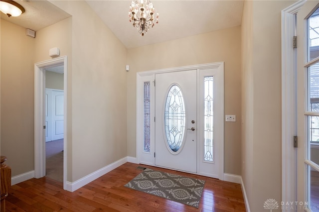 entrance foyer featuring an inviting chandelier, baseboards, and hardwood / wood-style flooring