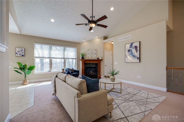 carpeted living room with visible vents, a textured ceiling, baseboards, and a premium fireplace