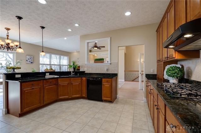 kitchen with under cabinet range hood, dark stone countertops, brown cabinetry, black appliances, and a sink