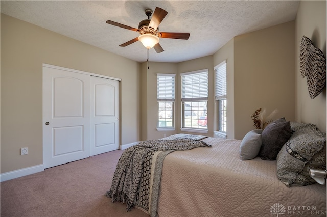 bedroom with a closet, baseboards, a textured ceiling, and carpet flooring