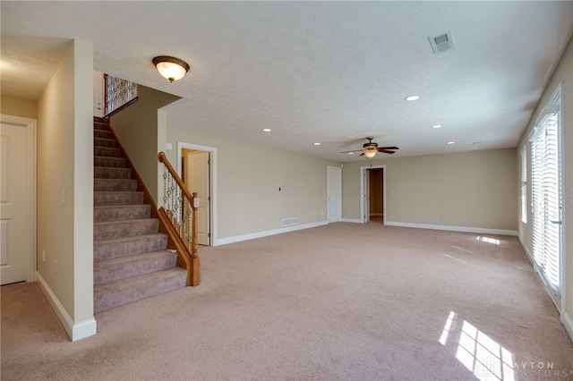 unfurnished living room featuring visible vents, a textured ceiling, stairs, and baseboards