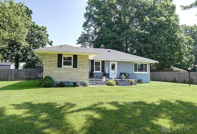 view of front of home featuring stone siding, a chimney, a front lawn, and fence