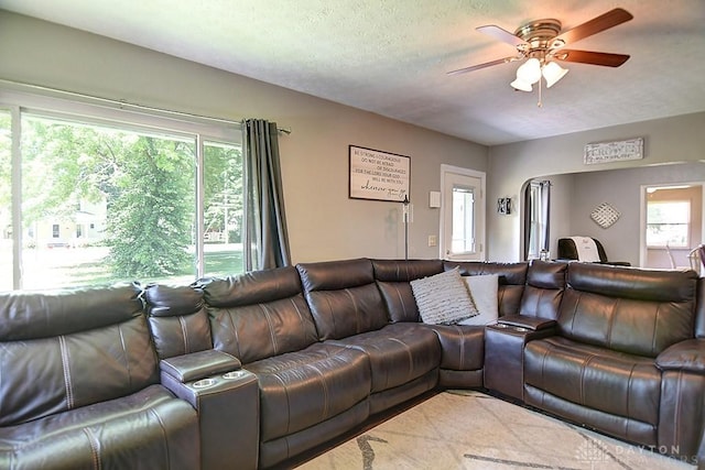 living room with ceiling fan, a wealth of natural light, and a textured ceiling