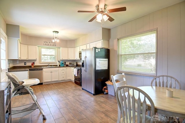 kitchen with dark countertops, light wood finished floors, appliances with stainless steel finishes, and white cabinetry