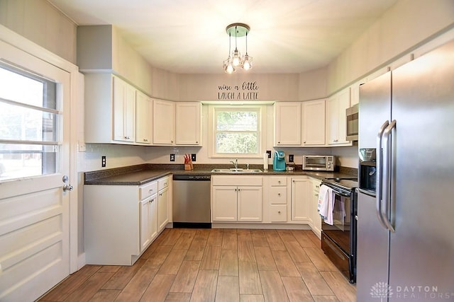 kitchen with a sink, dark countertops, white cabinets, and stainless steel appliances