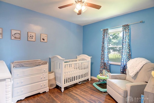 bedroom with a nursery area, wood finished floors, baseboards, and ceiling fan