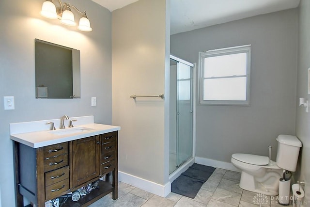 bathroom with a shower stall, toilet, vanity, and baseboards