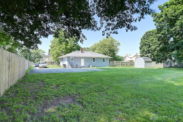 view of yard featuring a storage shed, an outdoor structure, and a fenced backyard