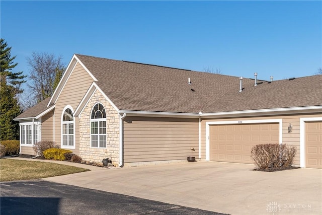 view of home's exterior featuring driveway, stone siding, and roof with shingles