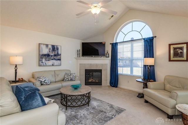 living area with a ceiling fan, visible vents, lofted ceiling, a tiled fireplace, and carpet flooring