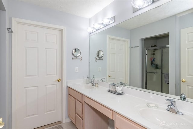 bathroom with a sink, a stall shower, and double vanity