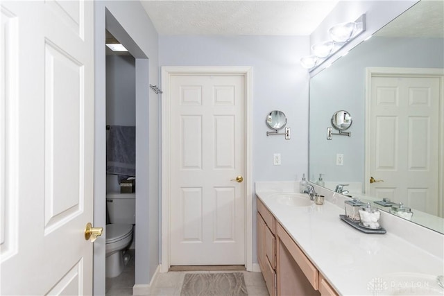 bathroom with a textured ceiling, vanity, and toilet