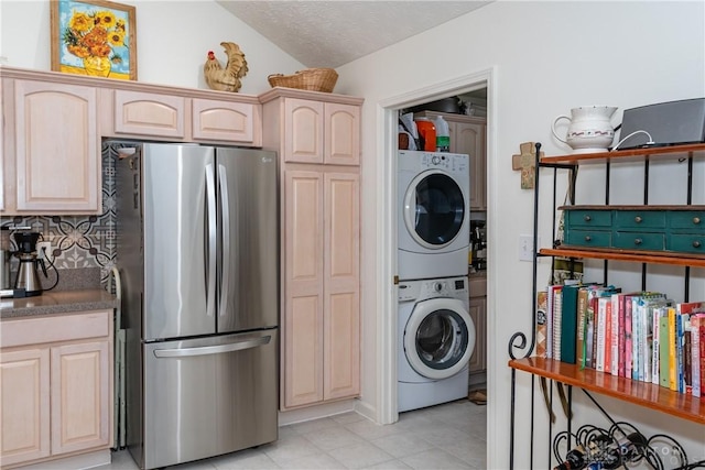 laundry area with light tile patterned floors, laundry area, a textured ceiling, and stacked washer and dryer