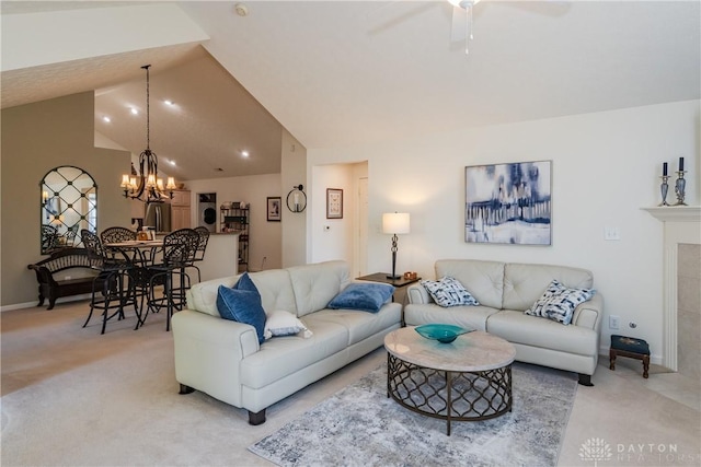 living room with light carpet, ceiling fan with notable chandelier, a tiled fireplace, and lofted ceiling