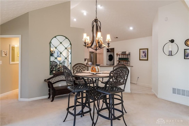 dining area with lofted ceiling, stacked washer and dryer, a notable chandelier, and light colored carpet