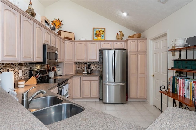 kitchen featuring light brown cabinetry, a sink, appliances with stainless steel finishes, light tile patterned floors, and decorative backsplash