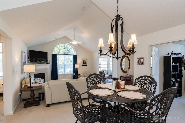 dining space featuring light carpet, ceiling fan, a tiled fireplace, and lofted ceiling