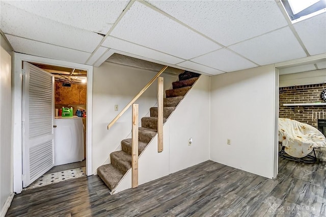 finished below grade area with washer / clothes dryer, stairs, a paneled ceiling, and wood finished floors